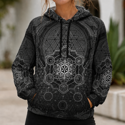 Woman wearing a black hoodie with geometric patterns outdoors.