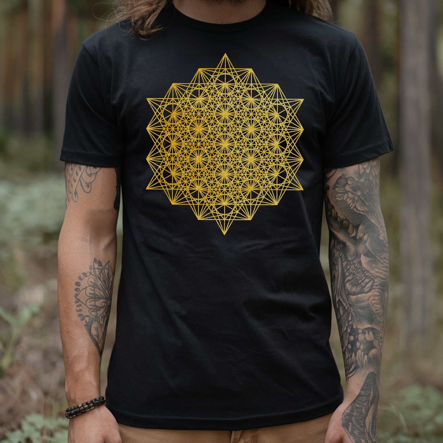 a man wearing a black t - shirt with a yellow flower of life on it